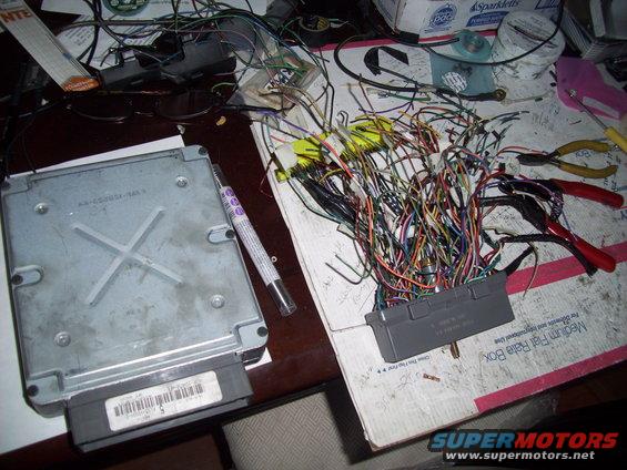 car engine computer and a messy bundle of wires with connectors