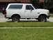 1994 Ford Bronco - Side view of a white 1994 Ford Bronco with a spare tire mounted on the rear.