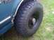 1994 Ford Bronco - Close-up of a teal SUV's fender and a large off-road tire, showing some rust damage.
