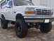 1994 Ford Bronco - This lifted 1994 Ford Bronco features a prominent grille and large off-road tires.