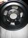 1994 Ford Bronco - A black wheel with a matte finish is shown, with a hand visible at the top edge.