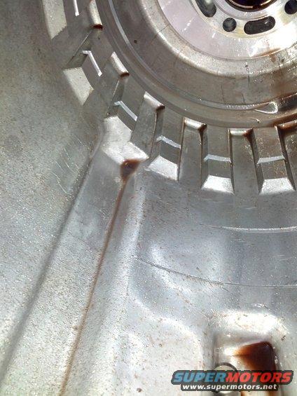 Close-up of a metal transmission housing with a toothed ring and dark fluid residue