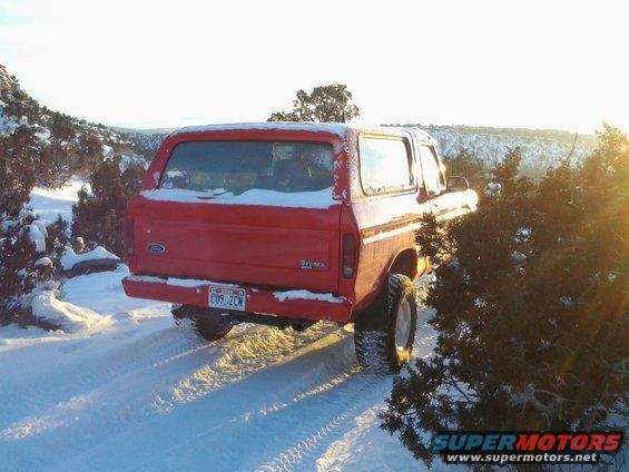 Red 1979 Ford Bronco driving on a snowy road