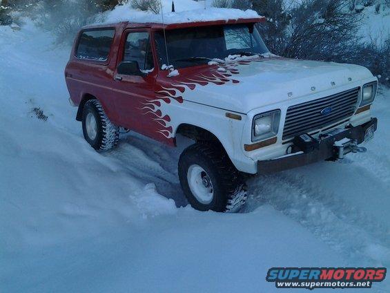 Ford Bronco with flame decals driving in snow. It has a winch on the front bumper