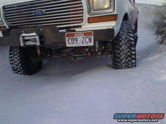 White 1978 Ford Bronco front end with winch, Utah license plate, and large off-road tires in snow