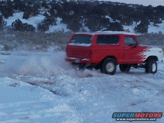 red and white SUV with flame decals driving through snow, kicking up snow