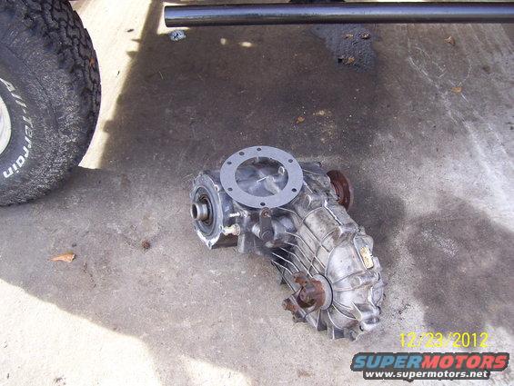 Transfer case with gasket on concrete, tire and frame above