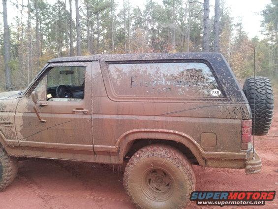Mud-covered SUV, side view, with spare tire on rear. Writing on window