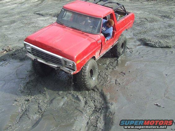 Red 1978 Ford Bronco off-roading in mud