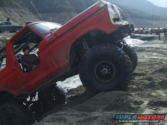 Red off-road vehicle with large tires navigating sandy terrain