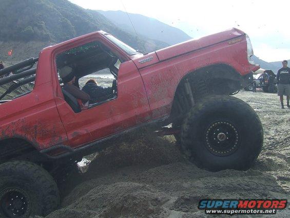 Red 1978 Ford Bronco on sand with large tires