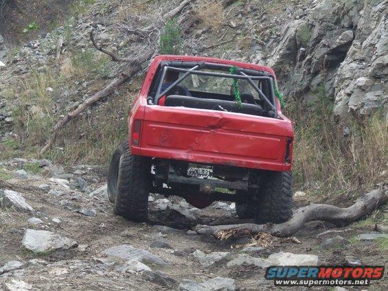 1978 Ford Bronco with roll cage on rocky trail, rear view