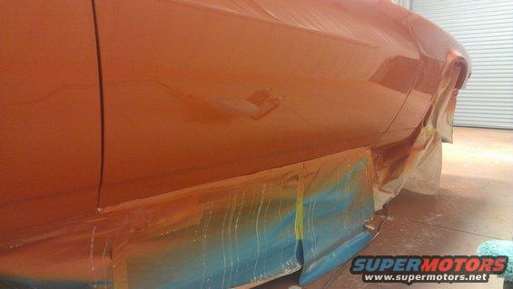 Orange car side panel covered in masking tape