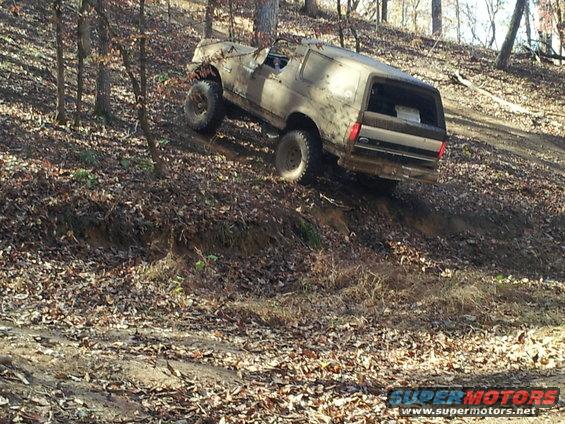 Muddy SUV climbing hill, 3q-front view. Bodystyle suggests 1980s