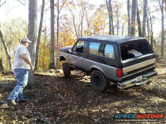 Two-tone grey and black Ford Bronco with lifted suspension on a dirt trail