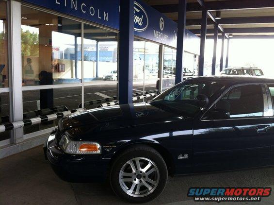 Dark blue 2007 Ford Crown Victoria sedan, front passenger side view, parked in front of a dealership