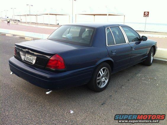 Dark blue 2007 Ford Crown Victoria parked on asphalt near a waterfront promenade