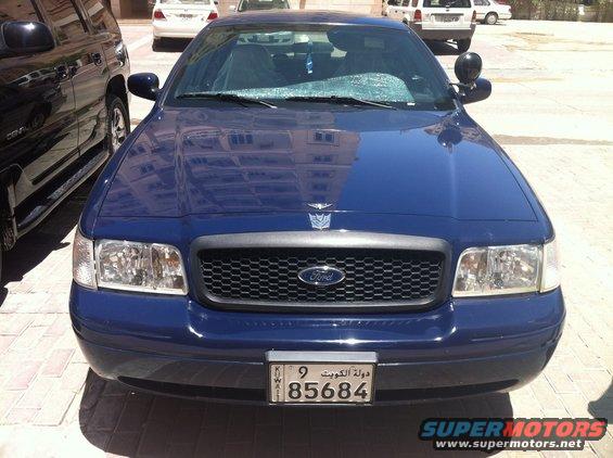 Blue 2007 Ford Crown Victoria front view, parked next to a black SUV. License plate visible