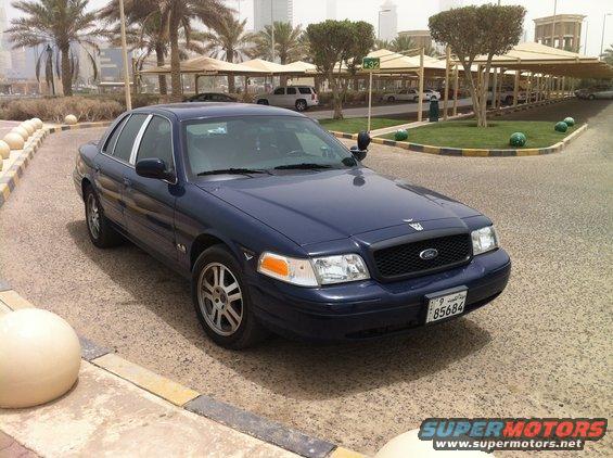 Dark blue 2007 Ford Crown Victoria parked outside with palm trees and buildings in the background