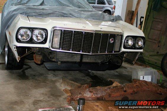 1976 Ford Ranchero front end with dual headlights and chrome grille, partially covered by a tarp