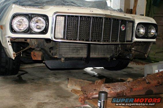 Front of a 1976 Ford Gran Torino with its bumper removed, showing the grille and headlights