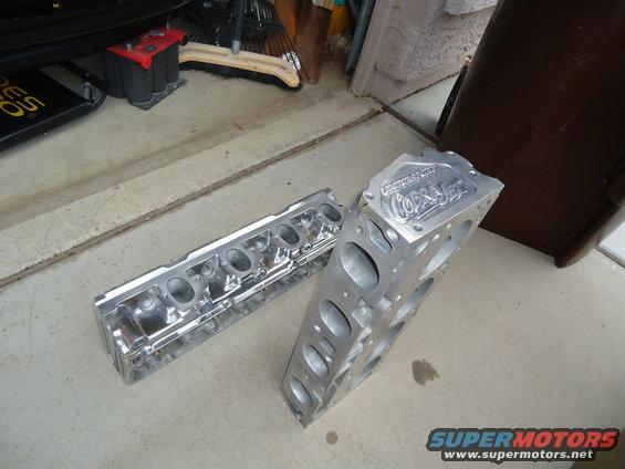 Aluminum engine block with 'Cobra Jet' lettering and cylinder head on concrete