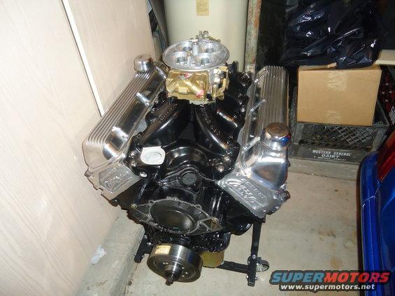 Black V8 engine on stand with chrome valve covers and carburetor