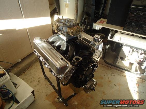 V8 engine with chrome valve covers and carburetor on a stand