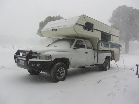 White 1997 Dodge 3500 pickup truck with camper shell in snowstorm