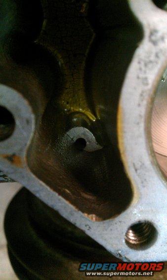 Close-up of engine part with oil residue and a small hole