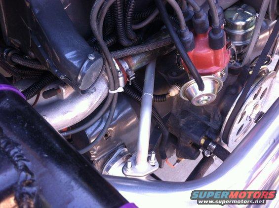 Engine bay with distributor, hoses, and fan belt visible. Some purple accents on frame