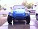 1970 Volkswagen Beetle - A modified blue Volkswagen Beetle sits on a wet driveway, parked next to a pickup truck and another vehicle.