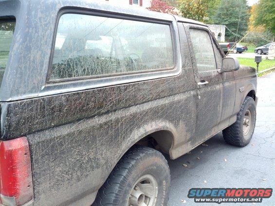 Mud-covered black Ford Bronco, side view, showing the rear quarter panel and door