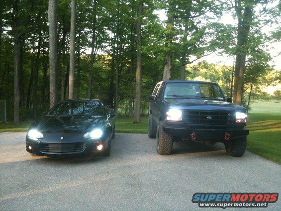 black sports car and lifted black SUV parked side-by-side