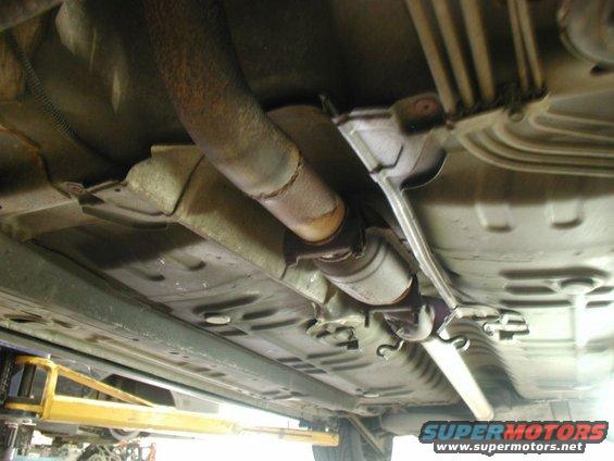 Underside view of a car's exhaust system, showing the catalytic converter and pipes