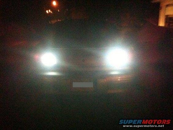 Car headlights on at night, showing the front of the vehicle