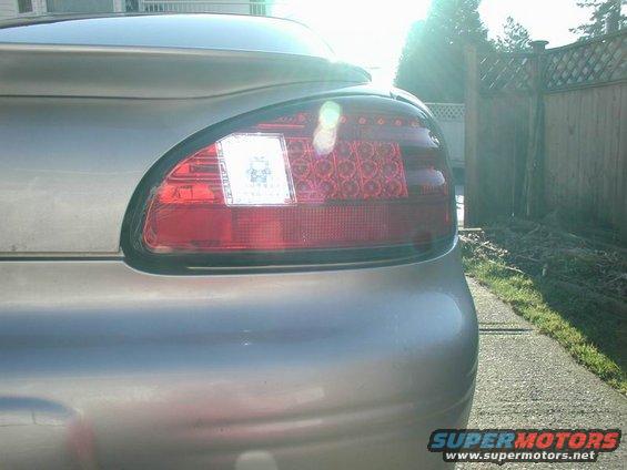 Silver car's rear driver-side taillight assembly with clear reverse light section and red LED brake lights