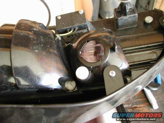 Close-up of a black car tail light assembly with a clear lens and internal components. A white circular bulb holder is visible