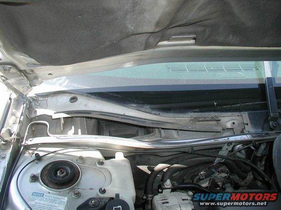 Under hood view of car's engine bay, showing windshield wiper assembly and engine components