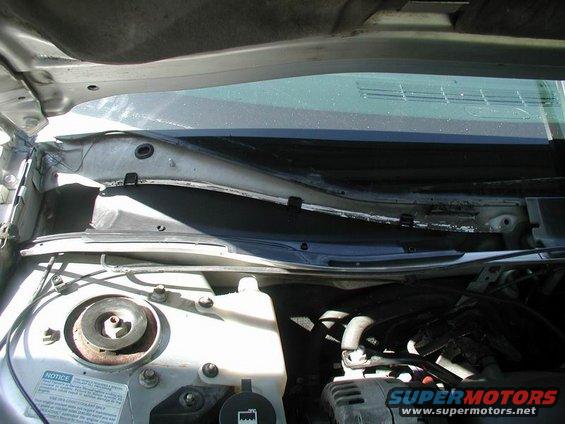 under hood view of car's cowl and part of engine bay