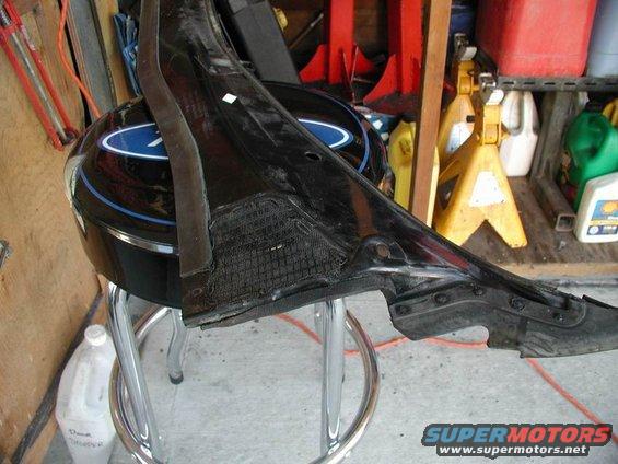 Black car part with textured insert resting on a chrome stool in a garage