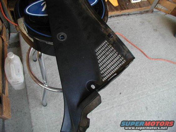 Black plastic cowl vent grille with a mesh section, resting on a stool