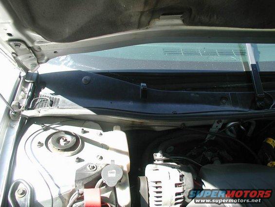 Silver car cowl and engine bay with black plastic trim and windshield wiper assembly