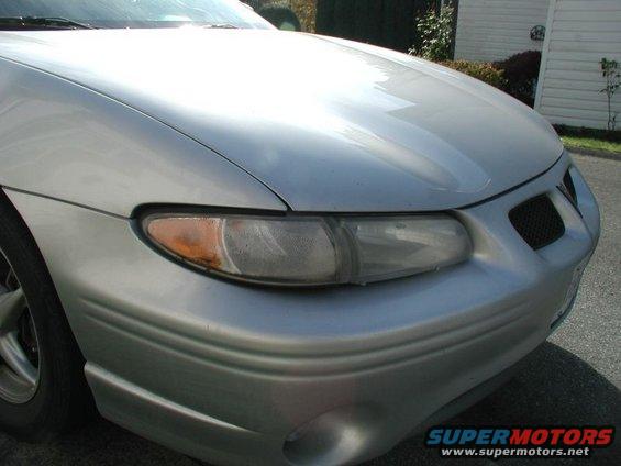 Front corner of silver 2002 Pontiac Grand Prix. Shows headlight, grille, and part of hood