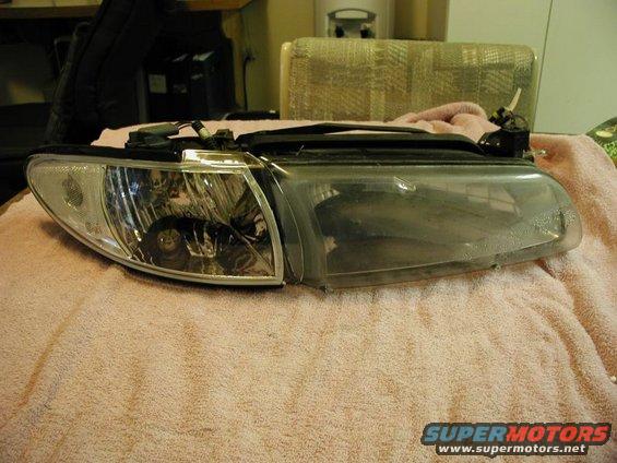 Car headlight assembly with clear lens and internal reflectors, resting on a pink towel