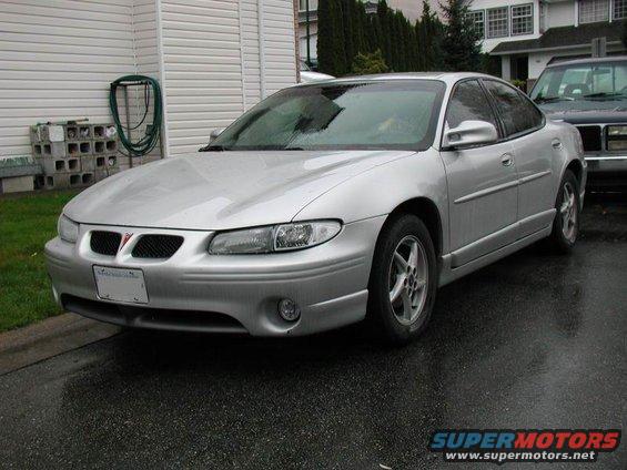 Silver 2002 Pontiac Grand Prix parked on wet asphalt, front quarter view. Another vehicle is partially visible to the right