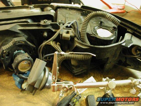 Car headlight assembly with wiring and bulb socket. Text on bulb reads 'SYLVANIA'