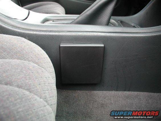 Passenger seat and center console area of a car, showing a closed black cup holder