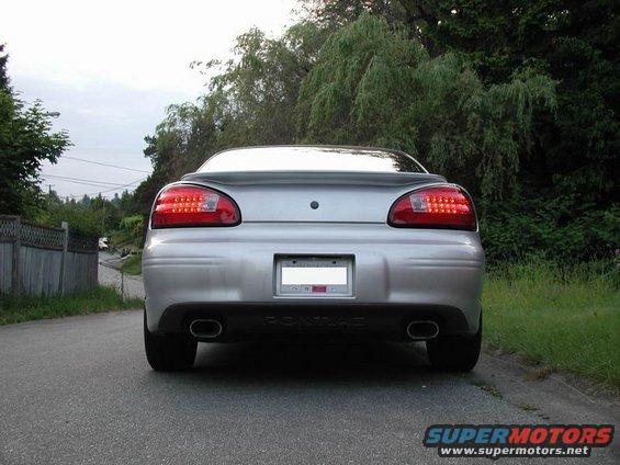 Silver sedan rear view, showing taillights, dual exhaust, and a license plate