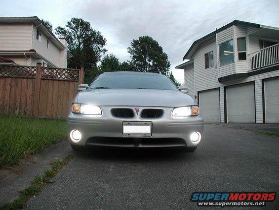 Silver 2002 Pontiac Grand Prix front view, headlights and fog lights on, parked in driveway